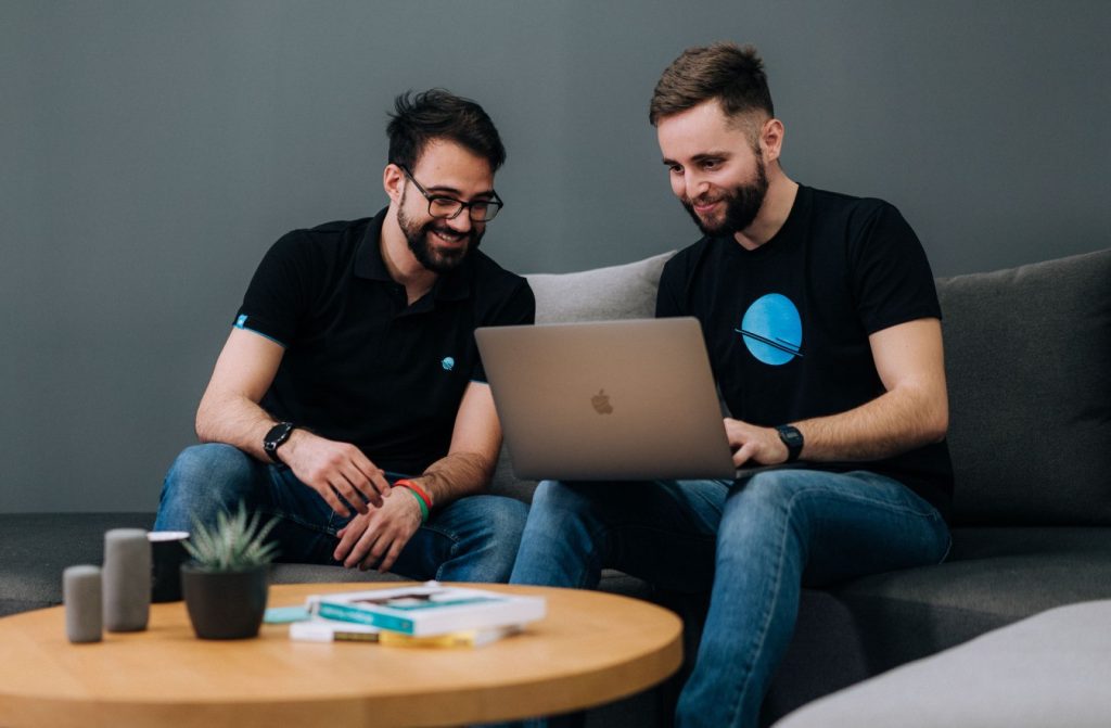 People sitting in front of a laptop and discussing their projects