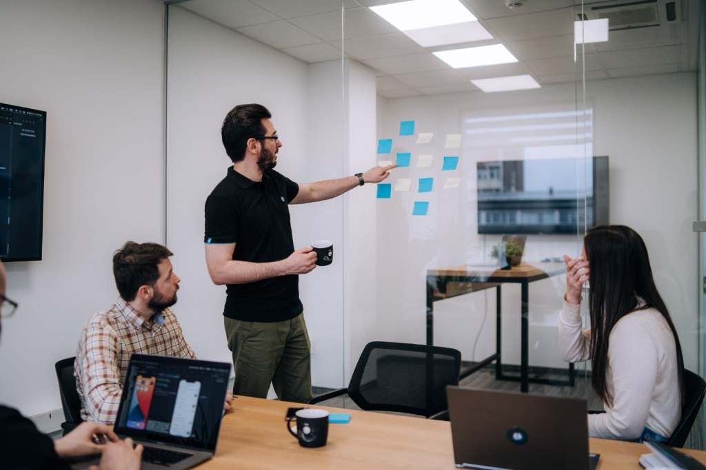 People  in front of a idea board, jotting down ideas for a project brief